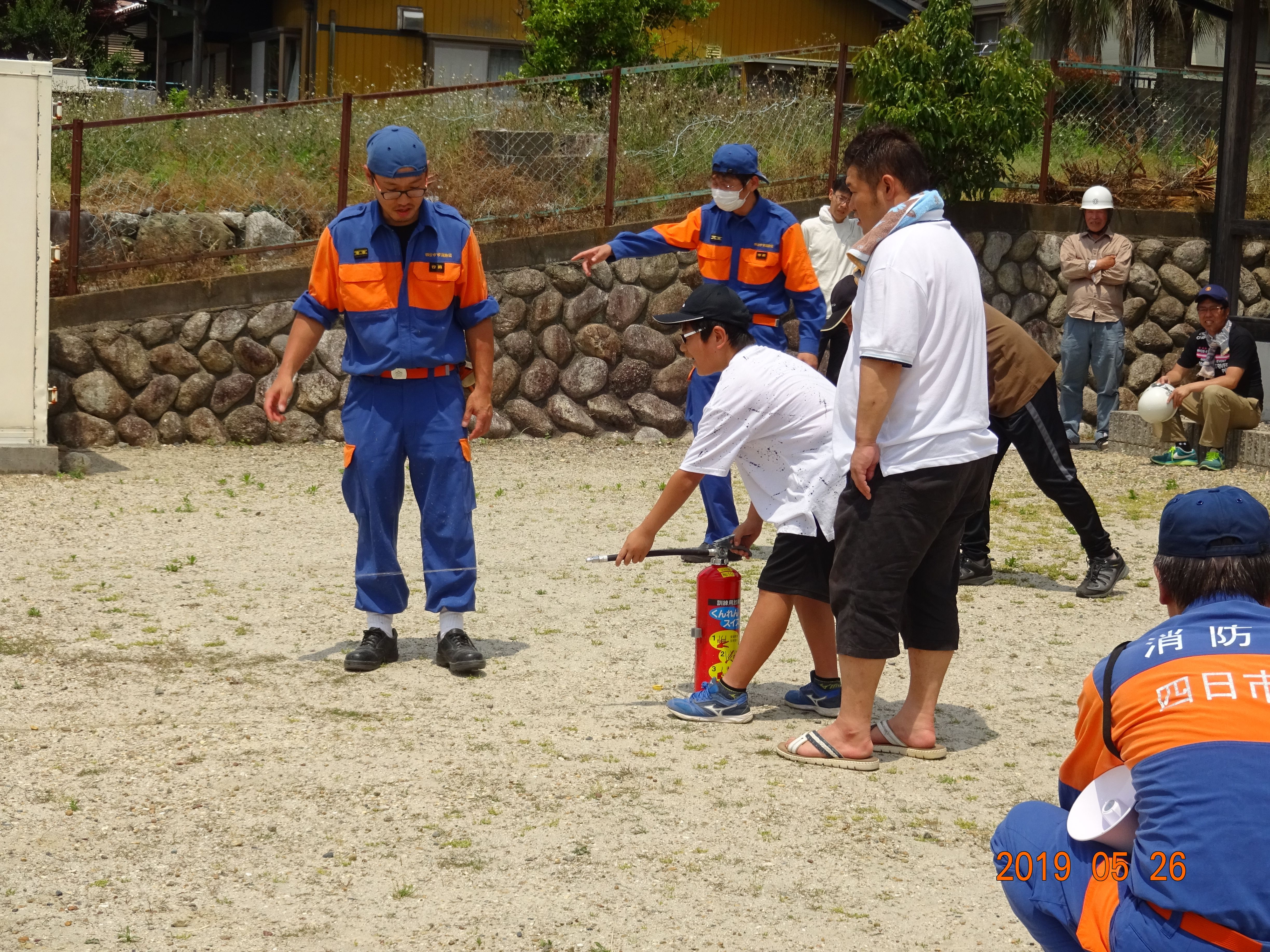 室山町防災訓練で水消火器を子供たちに指導する分団員