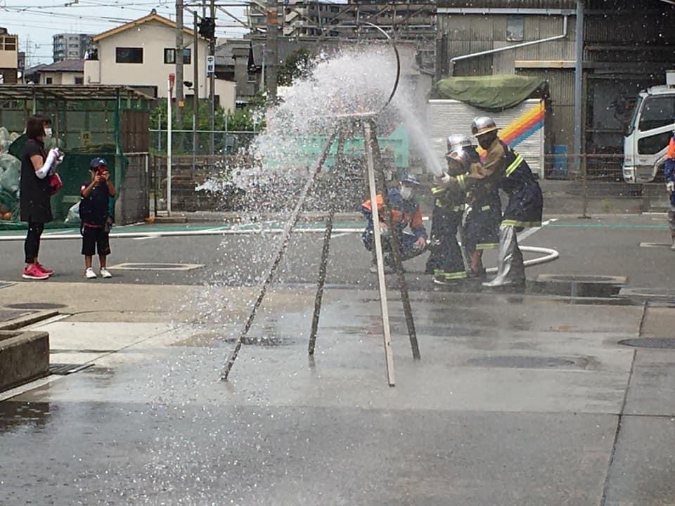 的に向かって放水する消防団と子ども